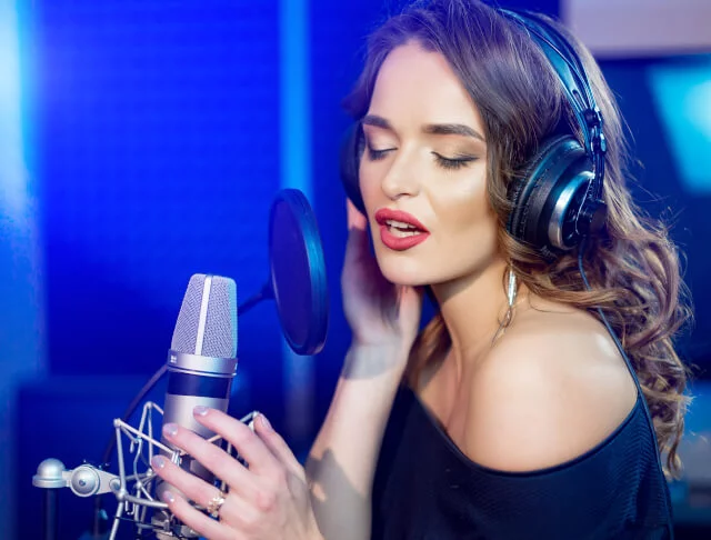 Mulher cantando em stúdio com fones de ouvidos