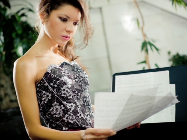 mulher lendo folhas de partituras - entender o que é partitura