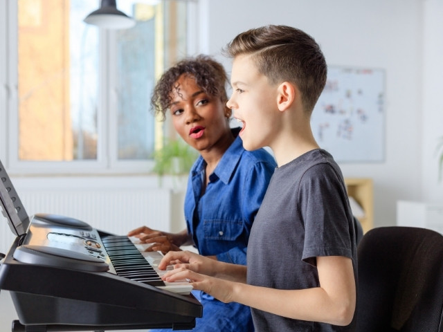 Professora de canto passando exercícios de vocalises para seu aluno