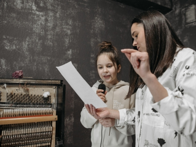 Professora dando aula de canto para uma menina