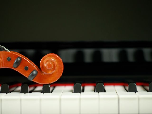fotografia cabo do violino sobre as teclas de um instrumento com teclado. Muito utilizados na música barroca