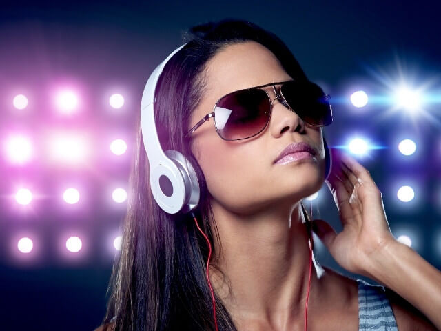 Mulher de óculos escuro em um fundo com luzes escutando música moderna