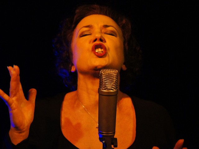 cantora se apresentando, cantando com olhos fechados e concentrada