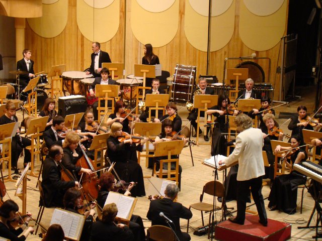 orquestra sinfõnica tocando acompanhada do maestro profissional