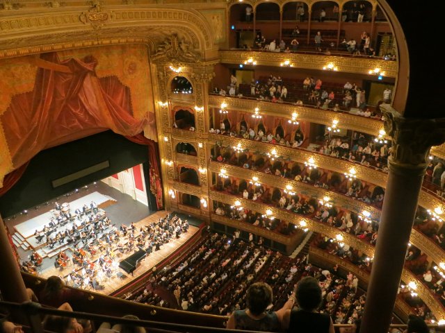 linda fotografia de um espaço para eventos com arquiterura retrô. No palco um orquestra sinfônica se apresenta