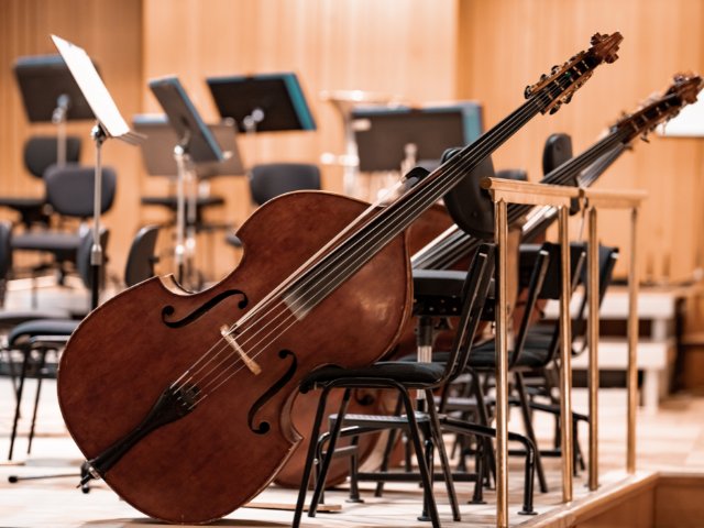 fotografia de um violino ao fundo várias cadeiras e suporte com partituras