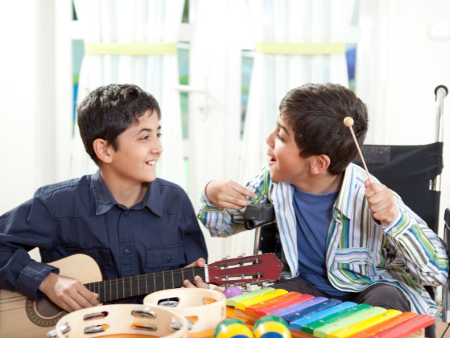 Crianças sorrindo enquanto praticam musicoterapia