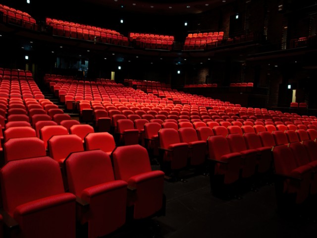 Fotografia de um espaço para apresentações teatrais, as cadeiras são vermelhas e sofisticads o espaço esta vazio